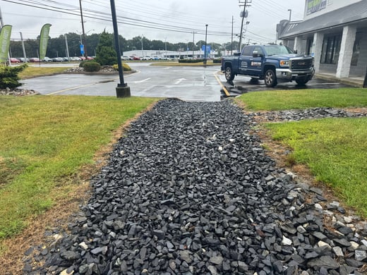 Route 37 parking lot in Toms River with corrected drainage swale and FixAsphalt service truck after stormwater repair project.