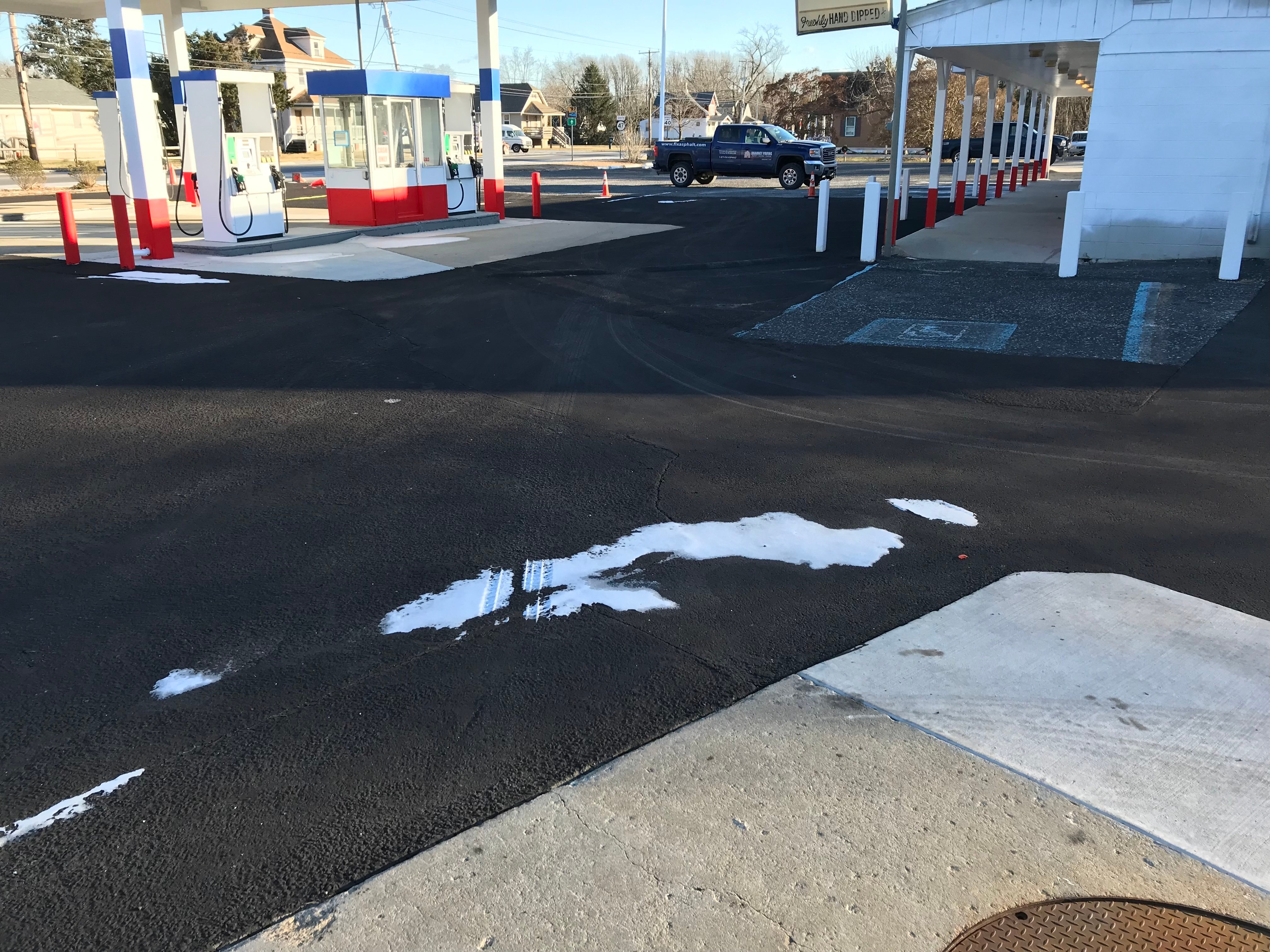 Parking lot with winter snow showing widespread sealcoat failure from freezing temperatures.