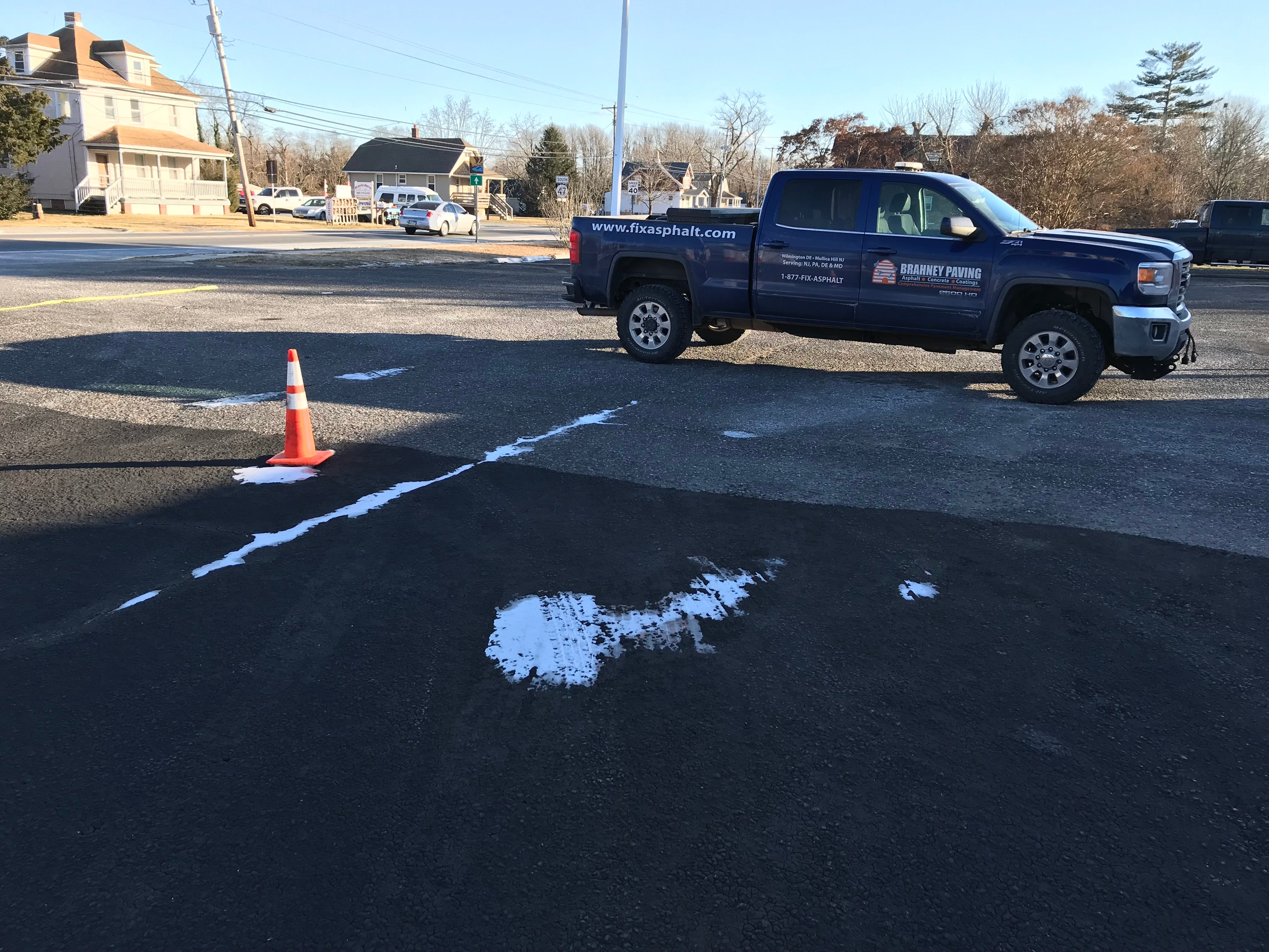 Parking lot with winter snow showing widespread sealcoat failure from freezing temperatures.