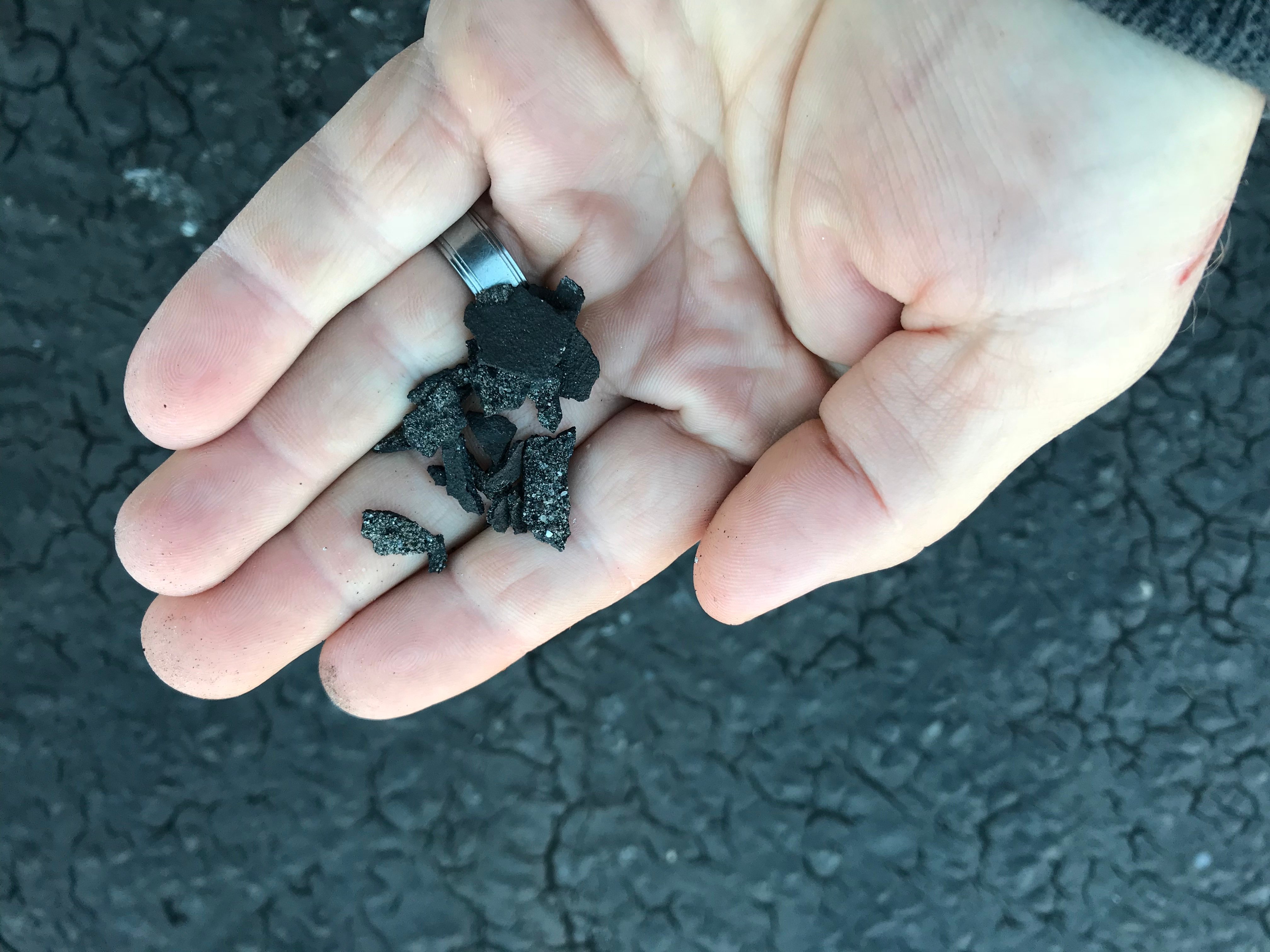 Asphalt parking lot with sealcoat peeling and flaking due to winter temperatures and improper curing