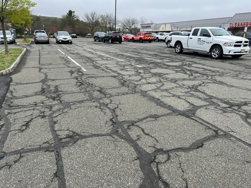 Parking lot with severe alligator cracking, potholes, and structural base failure, not suitable for sealcoating