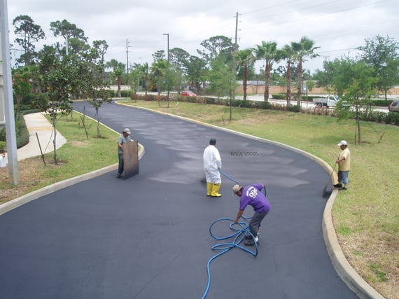 Crew applying asphalt sealcoat to a commercial parking lot in Jupiter, FL to protect pavement from sun, rain, and daily traffic wear.